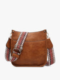 Brown leather handbag with decorative straps on a white background
