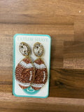 Pair of beaded earrings on a Taylor Shaye card against a wooden background